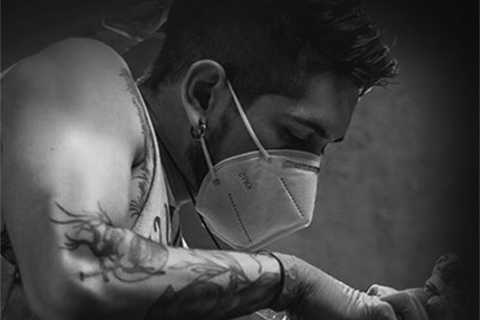 Experienced tattoo artist wearing a mask